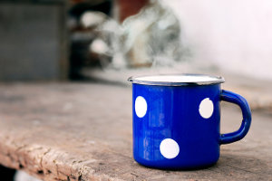 A blue polka dot mug with something steaming hot in it