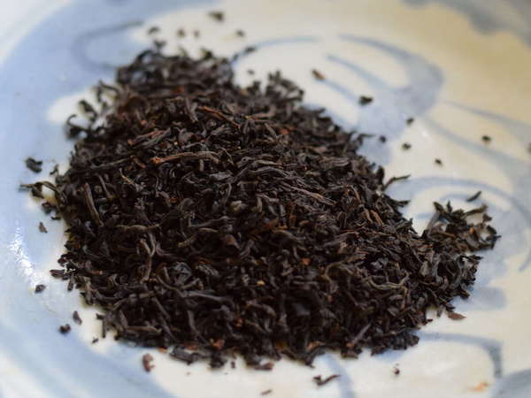 Fine-textured loose-leaf black tea on a pale blue-and-white plate