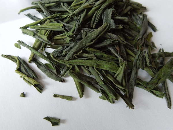 Loose-leaf green tea with straight, somewhat rolled leaves, vibrant green in color
