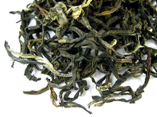 Loose-leaf oolong tea with dark green, twisted leaves, a few silvery-golden