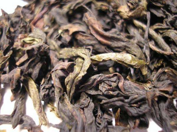 Closeup of tea leaves showing twisted, wrinkly shapes, colors ranging from dark reddish-brown to light olive-green