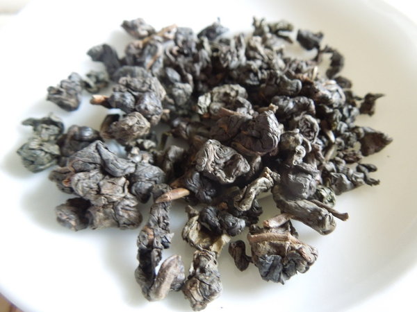 Tightly rolled oolong tea leaves showing grayish-brown color with a faint greenish tint