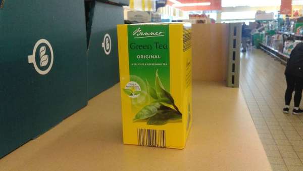 Yellow and green box reading Benner Green Tea Original, on shelf in supermarket