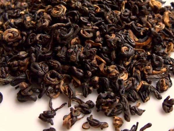 Tightly-rolled black-and-orange tea leaves, some almost snail-shaped