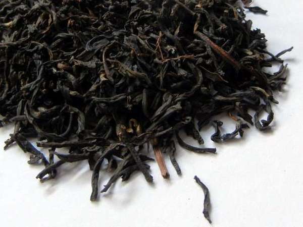 Loose-leaf tea showing slightly curved, mostly-whole leaves, a few stems in the mix