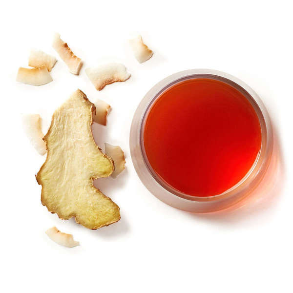 Thinly-sliced ginger root and shredded coconut alongside a bright red cup of herbal tea