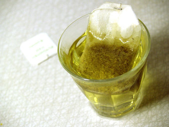A glass of chamomile tea brewed with a teabag, with a light golden color