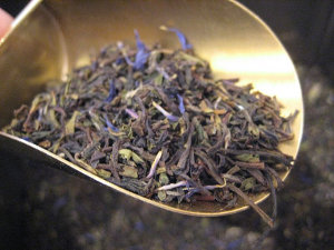 Loose black tea with flowers in a metal scoop