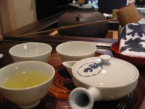 Green tea in a traditional Japanese cup with other teaware nearby