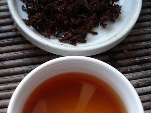 Wet black tea leaves with a dark brown color, and brewed tea liquor below