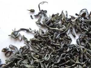 Loose leaf chun mee, showing small gray-green, slightly curved tea leaves