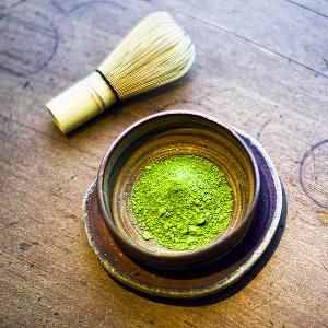 A bowl with matcha powder, and a whisk for preparation on the side