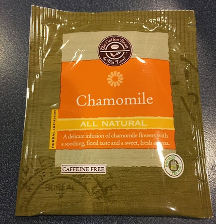 Sleek, neat looking teabag wrapper with The Coffee Bean & Tea Leaf logo, reading Chamomile on an orange background, All Natural on a yellow background, then: A delicate infusion of chamomile flowers with a soothing, floral taste and a sweet, fresh aroma. 
