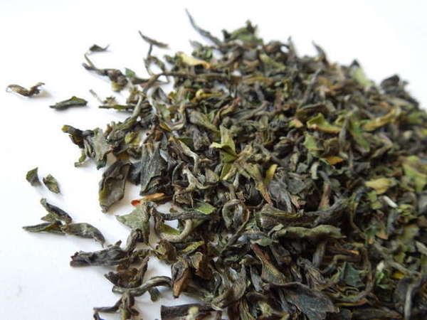 Fine-textured tea leaves with olive to yellowish-green color, silvery hints, and short, curved shapes