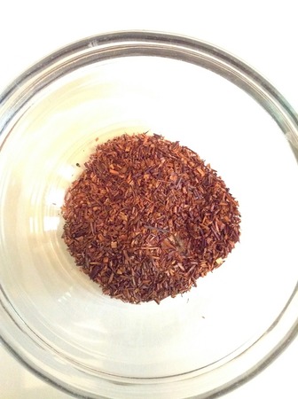 Loose-leaf red rooibos, fine broken twiggy texture, in a glass dish