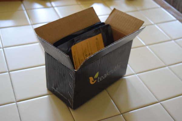 Black box with Teakruthi logo, containing bags of tea, on tile background