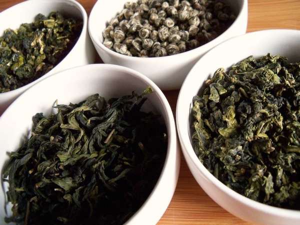 Four white bowls with four different loose-leaf teas with visually distinct textures