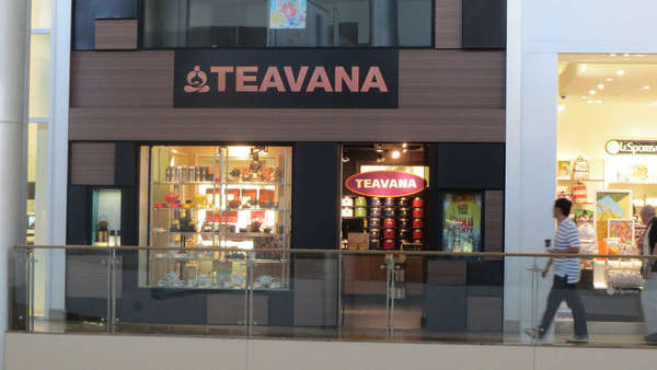 Storefront with Teavana sign above and inside, display in window on left, some other mall shop on right