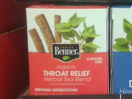 Closeup of box of  Benner Tea Co Organic Throat Relief, red background, showing picture of herbs behind logo