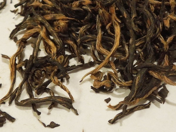 Loose-leaf black tea with long, intact, wiry leaves, slightly orangeish