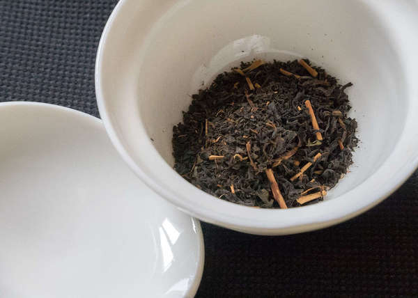White dish filled with loose-leaf black tea showing numerous orange stems