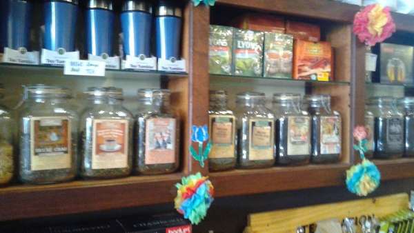 Tea in glass jars on wooden shelves against a wall
