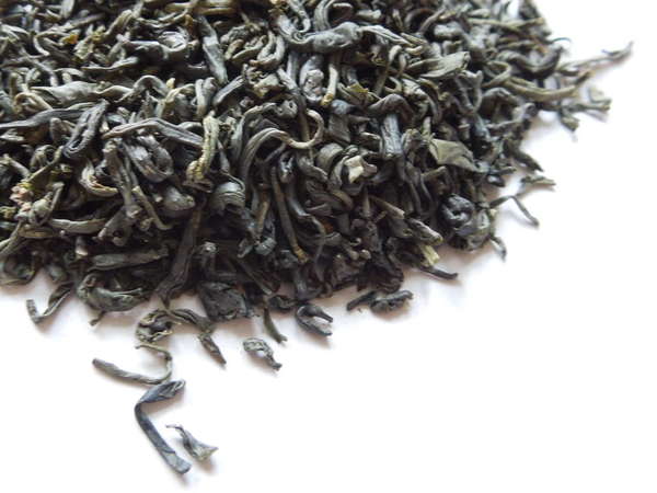 Loose-leaf green tea with gray-green appearance, somewhat curly shape, on white background