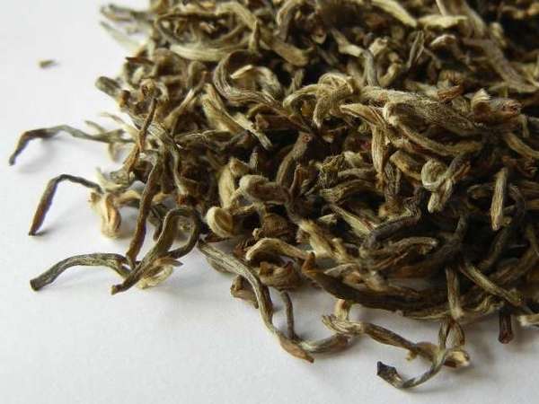 Loose-leaf tea with silvery-yellow color, downy hairs, and narrow, moderately curly shape