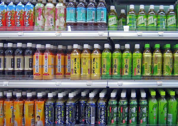 Three rows of shelves with various bottled teas with colorful labels with Japanese characters