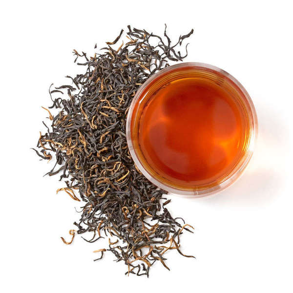 Loose-leaf black tea with long, wiry leaves and golden-orange tips, cup with orange-red infusion