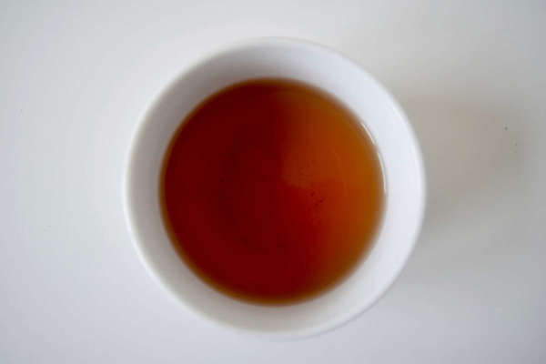 Plain white cup of tea with reddish color on plain white background