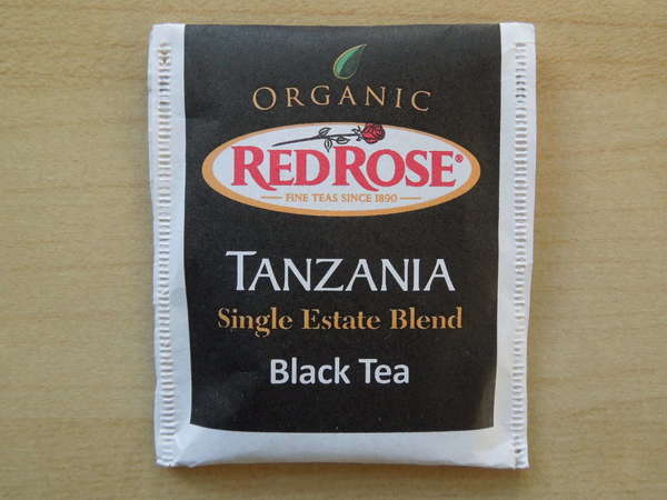 Tea bag wrapped reading Organic, Red Rose (Logo), Tanzania Single Estate Blend Black Tea, mostly black background with white trim