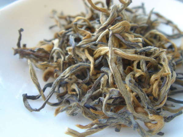Loose-leaf tea with pale orange, yellow, and grayish leaves, long, wiry, covered in fine white hairs