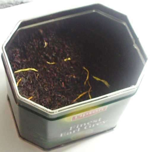 Loose-leaf fine-textured black tea with yellow strands, in an octagonal metal tin