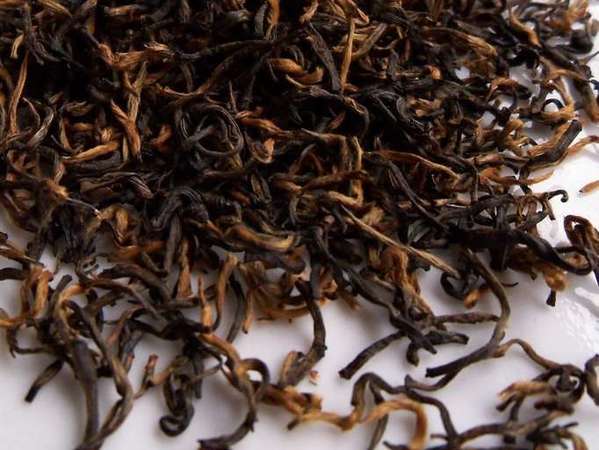 Narrow, curvy loose tea leaves showing mix of black and orange colors