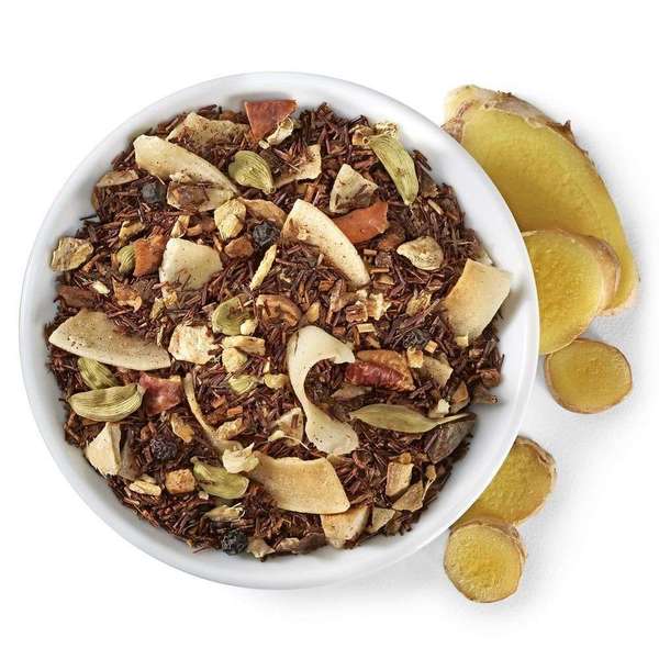 Loose-leaf rooibos with red-bronze color, green cardamom pods, pieces of shredded coconut and dried ginger root, in a dish with fresh sliced ginger root alongside