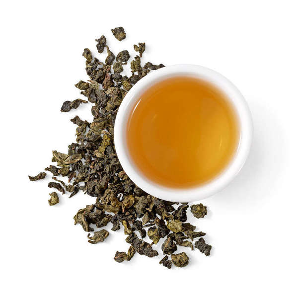 Golden-green pellets of tightly-rolled oolong tea, and a white cup with golden infusion