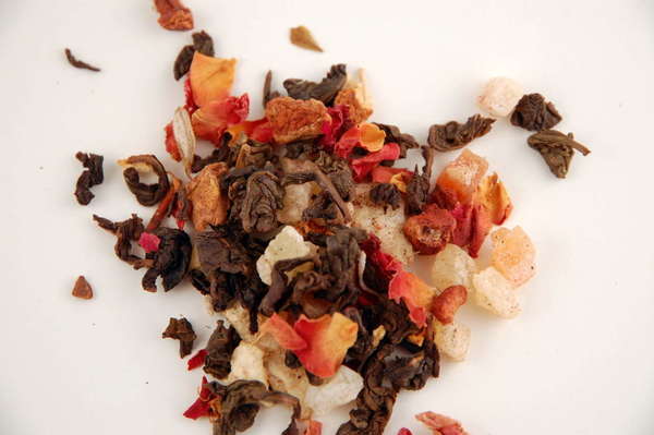 Mix of tightly-rolled brown oolong leaves and bright orange and white chunks of fruit