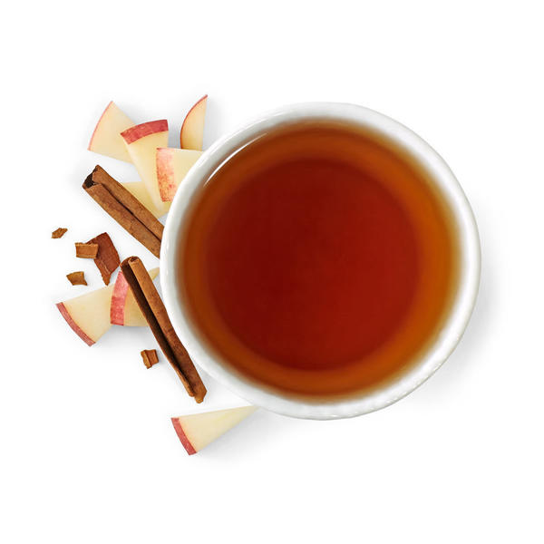 Dark brown cup of tea, with cinnamon sticks and apple slices on side