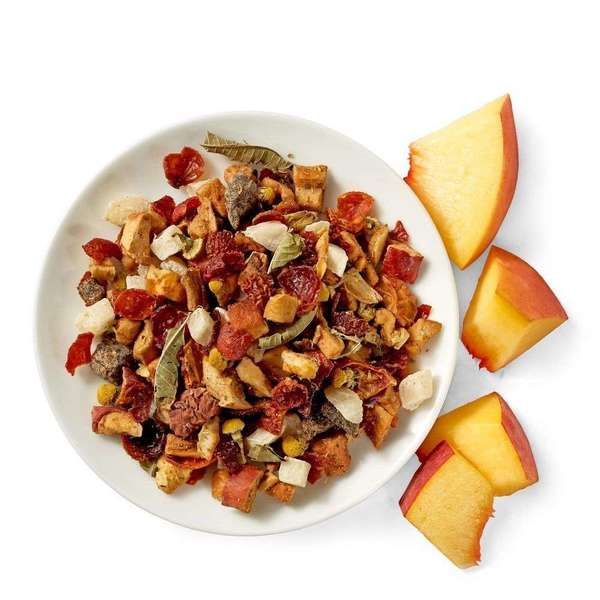 Fruit herbal tea with whole pieces of dried fruit in a dish, fresh peach slices on the right