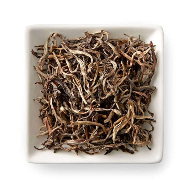 Wiry, curvy, pinkish-orange loose tea leaves in a square dish