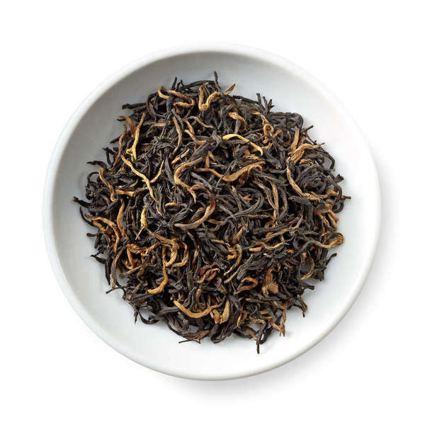 Loose-leaf black tea with long, intact dark leaves and some golden-yellow tips, in a white dish