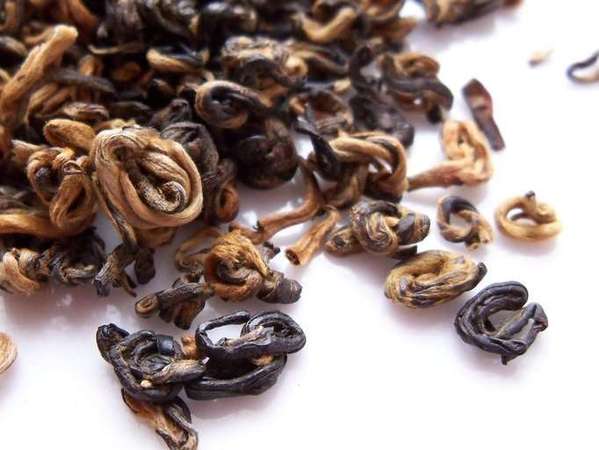 Loose-leaf tea with black and pale orange colors, tightly rolled into snail-like shapes