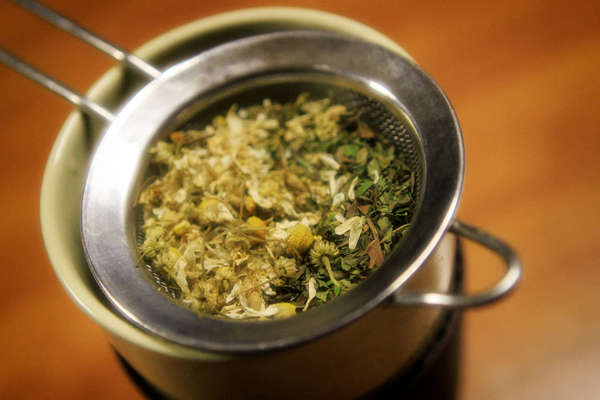 Cup with strainer containing dried chamomile blossoms